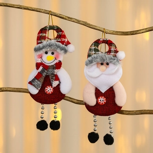 Detail of Christmas snowman and Santa fabric pendants hanging on branches with warm bokeh