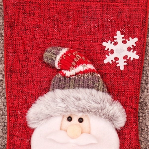 Detail of red fabric Christmas stocking featuring 3D Santa Claus and gray plush trim