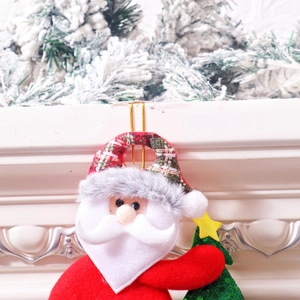 Detailed close-up of a plush Santa Claus ornament with a sequined Christmas tree and gold bell