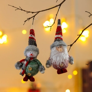 Close-up of knitted snowman and Santa tree ornaments with festive bokeh lighting