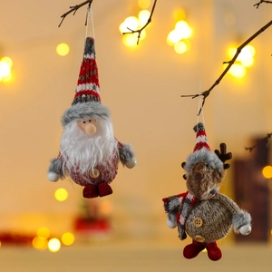 Detail of handmade knitted Santa and reindeer ornaments hanging on a rustic branch