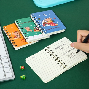 A7 mini Christmas spiral notebooks with reindeer and Santa covers on a dark green desk