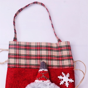 Detail of red felt Christmas gift bag with plaid trim and knitted hat snowflake decor