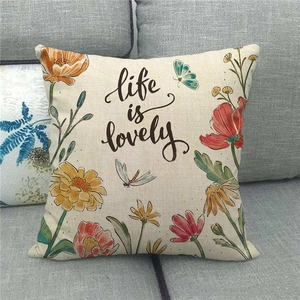 Funda de cojín de lino con flores acuarela y frase Life is Lovely en sofá gris