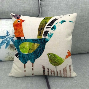 Close-up of linen pillowcase with artistic bird prints on a modern gray fabric sofa