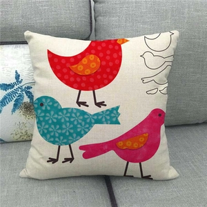 Linen pillowcase detail featuring colorful cartoon birds on a grey fabric sofa