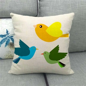 Linen throw pillow cover with three colorful cartoon birds on a grey fabric sofa