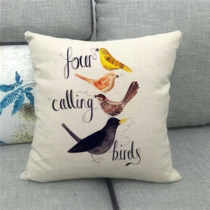 Detailed view of linen cushion cover with four colorful birds and festive typography