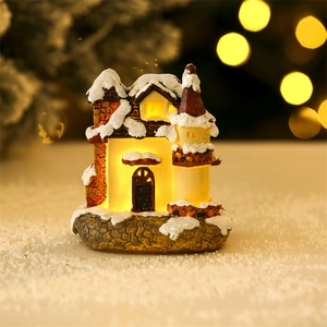 Close-up of a miniature glowing Christmas house with snow details and warm LED light