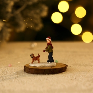 Close-up of a Christmas boy and puppy miniature figurine on snow base with bokeh light