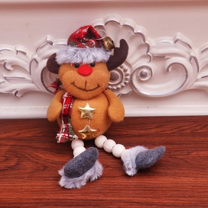 Close-up of Christmas reindeer ornament with plaid hat and golden bells on wood surface