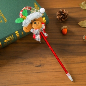Nahaufnahme eines Weihnachts-Kugelschreibers mit Plüschbär auf einem grünen Buch