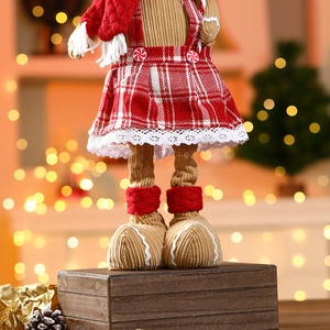 Detail of Christmas gingerbread doll in red plaid dress and knit scarf on wooden box
