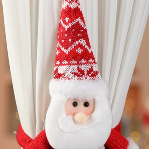 Détail de l'attache-rideau Père Noël en tricot fixé sur un rideau blanc plissé