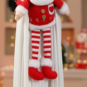 Détail d'une poupée de Noël en tricot avec pull à cœur et longues jambes rayées