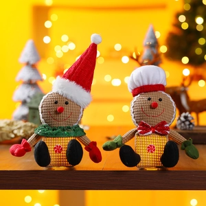 Plush light-up gingerbread man Christmas figurines with festive hats on wooden surface