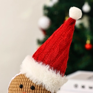 Close-up of plush gingerbread man toy with red knit hat and festive decor background