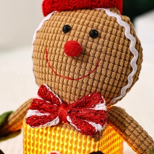 Close-up of glowing gingerbread man plush in corduroy with festive LED warm light