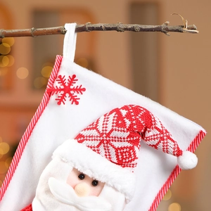 Détail d'une grande chaussette de Noël tricotée avec un Père Noël 3D sur branche