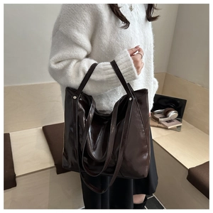 Macro shot of large dark brown tote bag in glossy patent leather finish with double handles