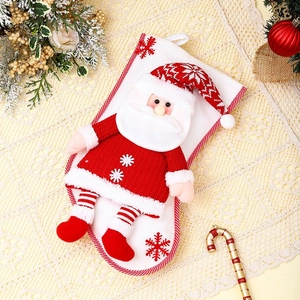 Détail d'une grande chaussette de Noël tricotée avec un Père Noël 3D et décor