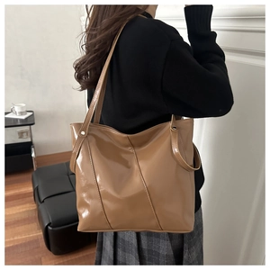 Detail of camel brown tote bag with V-shaped stitching and glossy leather texture