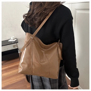 Detailed view of brown glossy faux leather tote bag with vertical stitching for women