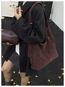 Détails du grand sac cabas bordeaux et sa pochette assortie portés en extérieur par un mannequin