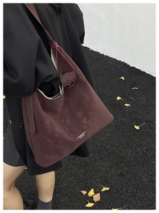 Vue détaillée de la texture du cuir bordeaux mat et de la large bandoulière du sac