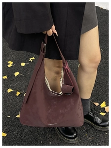 Détail du sac cabas en daim bordeaux montrant la texture mate et le logo gravé