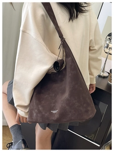 Détail de texture d'un grand cabas en daim marron avec logo en lettrage blanc