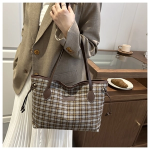 Close-up of a vintage plaid tote bag with brown leather handles and side drawstring details