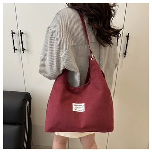 Dettaglio della borsa hobo in velluto bordeaux con etichetta moda sulla spalla