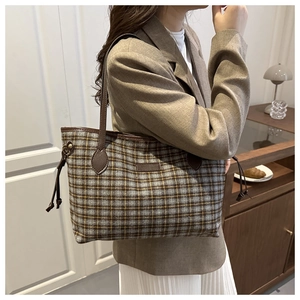 Close-up of stylish plaid tweed tote bag with fringe details and leather shoulder strap