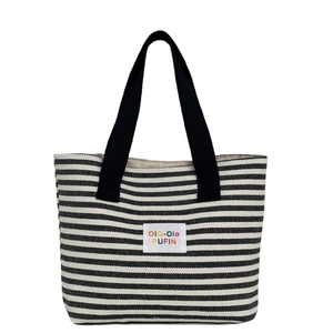 Large striped canvas tote bag with black handles and central logo patch for daily commute