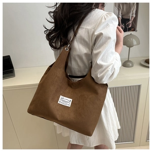 Detail of dark brown suede tote bag with fashion label and silver metal eyelet grommets