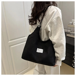 Detail showing the large capacity black suede tote bag with stylish white fashion patch