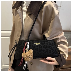 Dettaglio della borsa tote leopardata nera con logo dorato e ciondolo a forma di orso