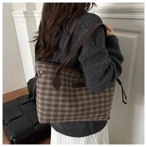 Detail of vintage plaid tote bag featuring brown and green check pattern and leather straps