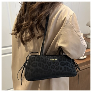 Dettaglio borsa sottobraccio leopardata con logo dorato e nappine su cappotto kaki