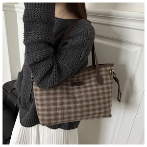 Detail of plaid patterned tote bag with brown leather shoulder straps worn by model