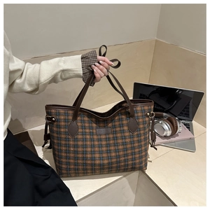 Close-up of retro plaid tote bag with brown leather handles in a cozy office setting
