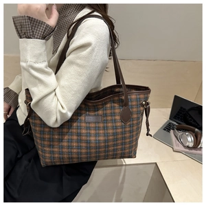 Detailed view of large plaid tote bag showing interior space with a laptop and books