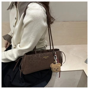 Detail view of brown leopard print faux suede tote bag with plush bear charm accessory
