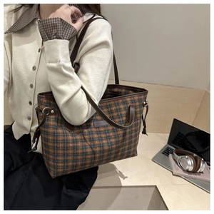 Lifestyle shot of large plaid tote bag with brown leather straps in office setting