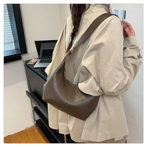 Detail shot of dark brown pebbled leather hobo bag worn by a model in office setting