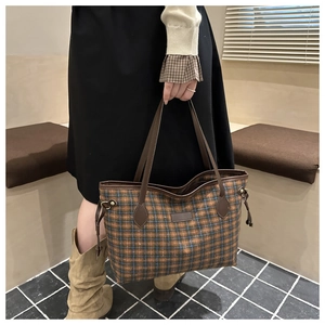 Plaid tote bag detail featuring brown leather straps and side drawstring on checkered fabric