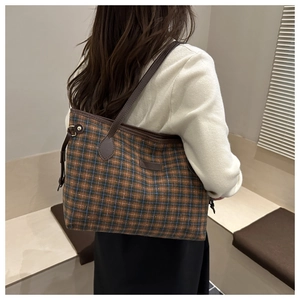 Detail of checkered tote bag showing thick plaid fabric and brown leather shoulder straps