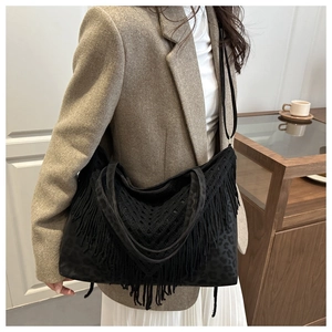 Close-up of a large black Hobo bag with fringe details and leopard print on a model