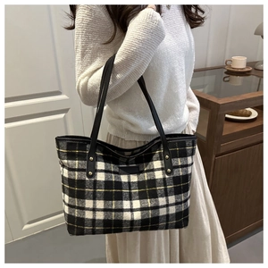 Close-up of a plaid tote bag with yellow and black patterns and leather patch details